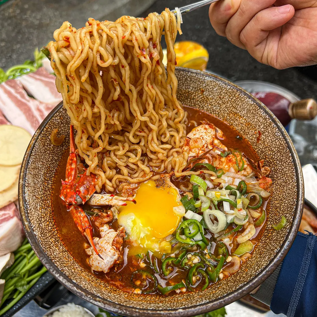 Blue crab ramen with an egg, noodles lifted from the broth · 이태원 고기집 · Itaewon Restaurants