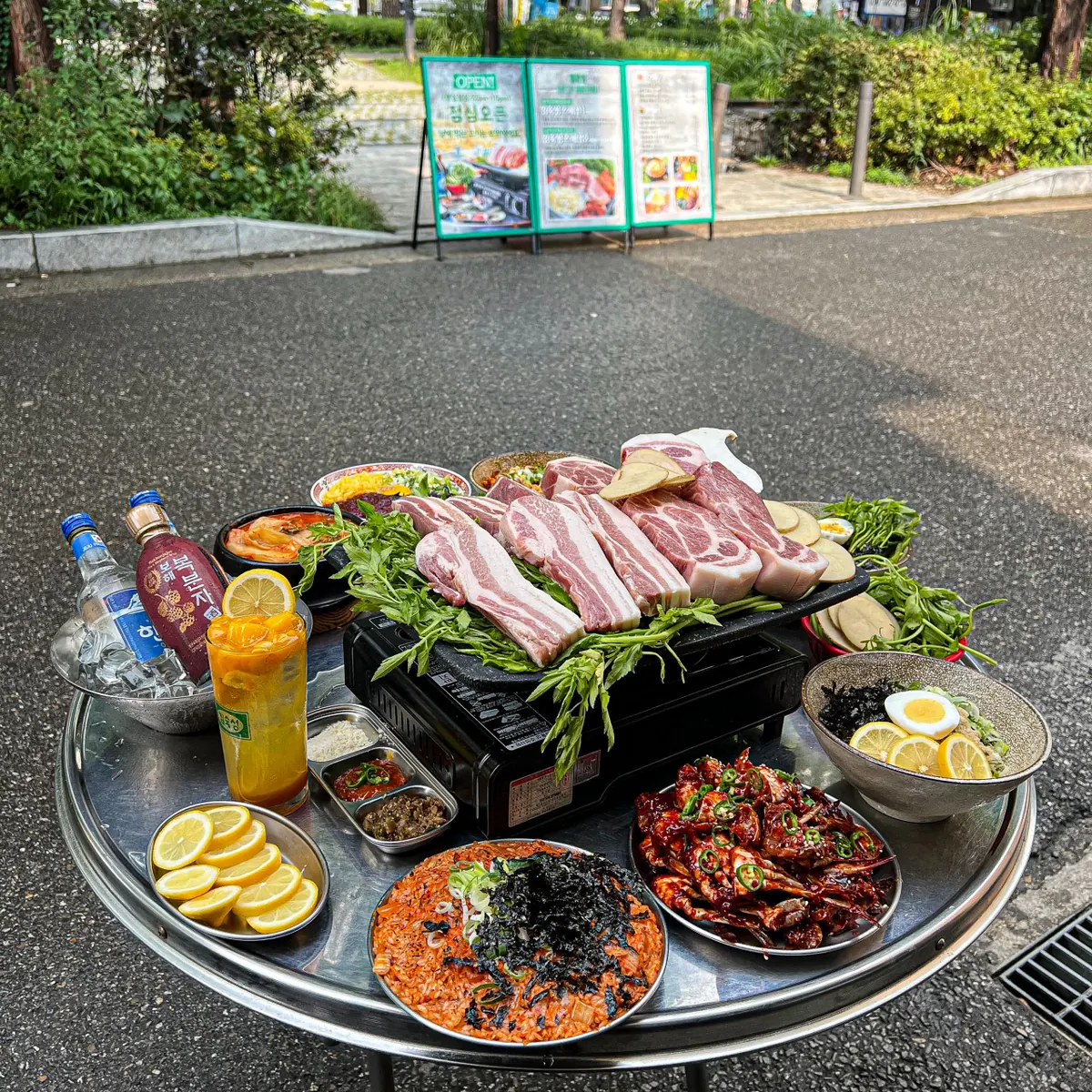 A full outdoor table at Kim Sukseong Itaewon — aged pork belly and minari on the grill, banchan all round · 이태원 맛집 · Itaewon Korean BBQ